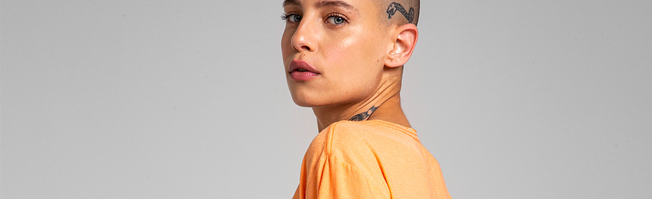 Mulher com cabelo raspado usando camiseta laranja