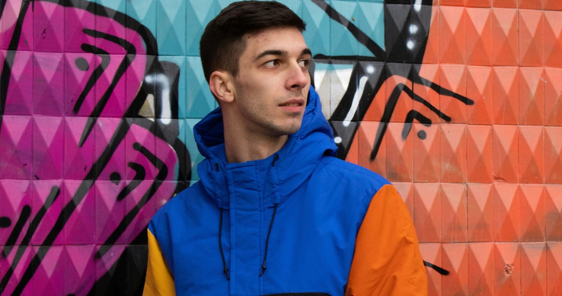 modelo com roupas coloridas e uma parede estampada de fundo