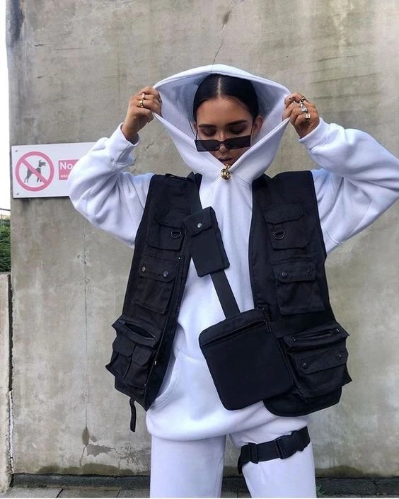 Modelo usando moletom oversized branco com colete cargo preto em look despojado com sobreposição