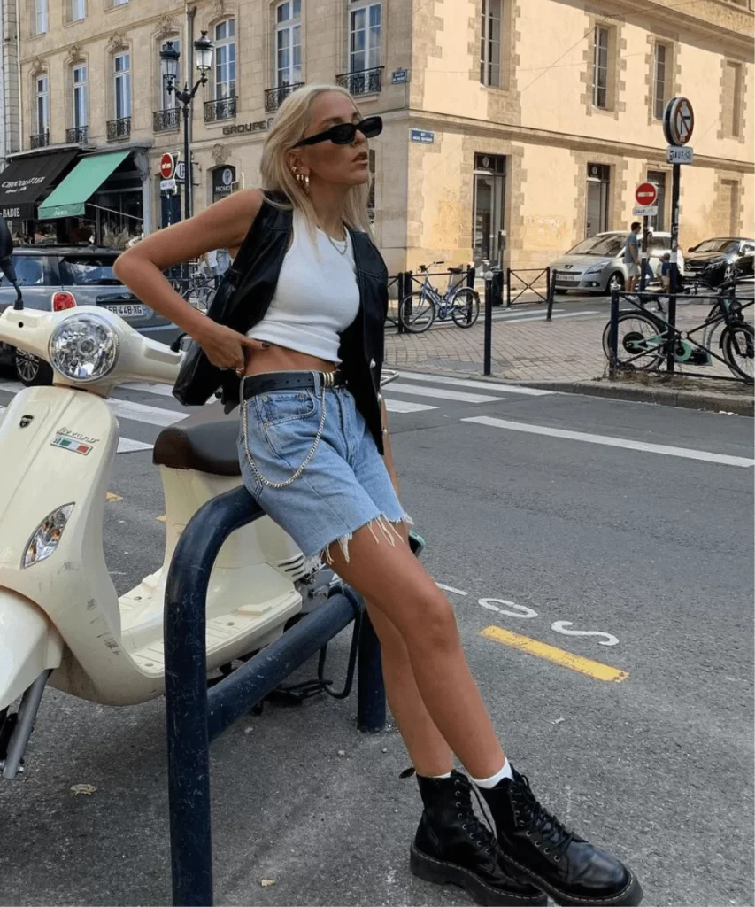 modelo feminina usando colete de couro com cropped branco e shorts jeans