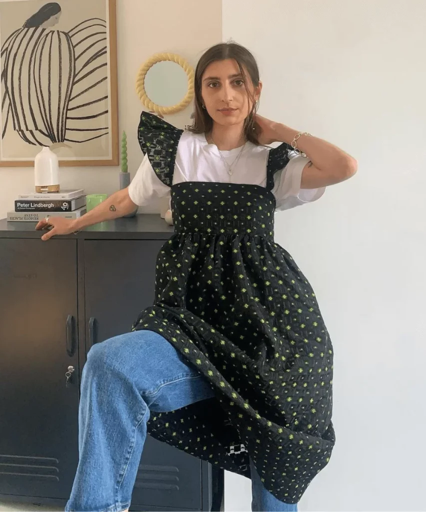 modelo usando vestido amplo sobre camisa branca e calça jeans