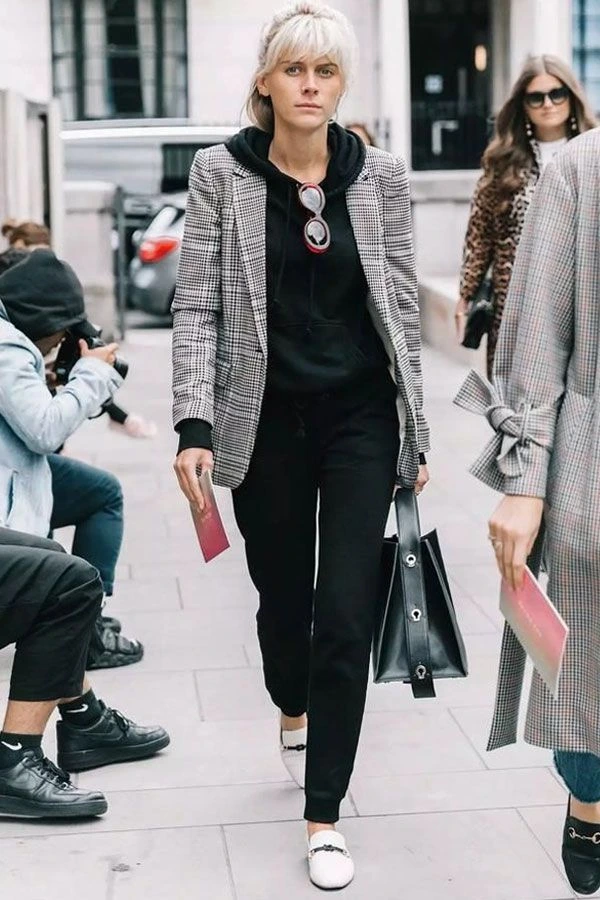 modelo usando moletom preto com blazer xadrez por cima