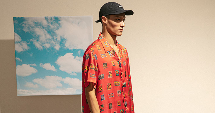 Modelo com boné preto e camisa rosa estampada