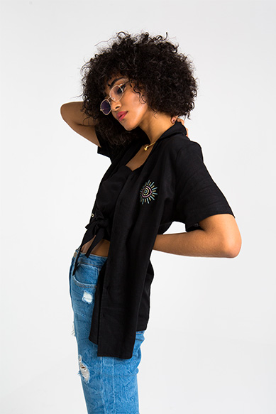 Mulher com cabelo cacheado em look estiloso.