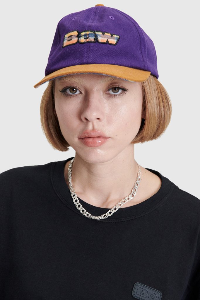 Modelo usando boné roxo com bordado colorido