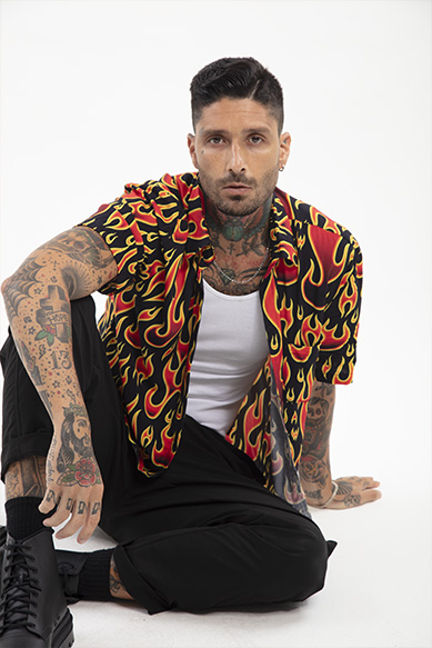 Homem tatuado sentado com camisa de chamas