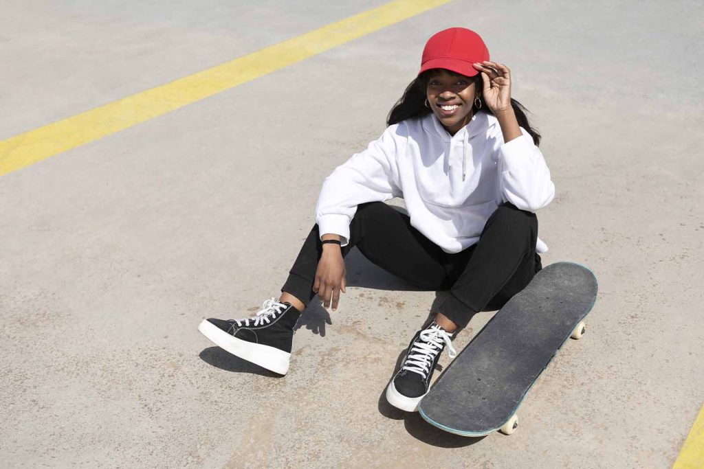 Jovem sorridente com skate e boné vermelho