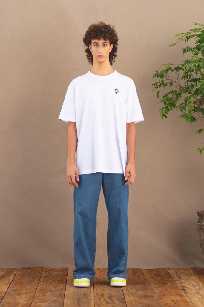 Modelo usando camiseta branca e calça jeans azul.