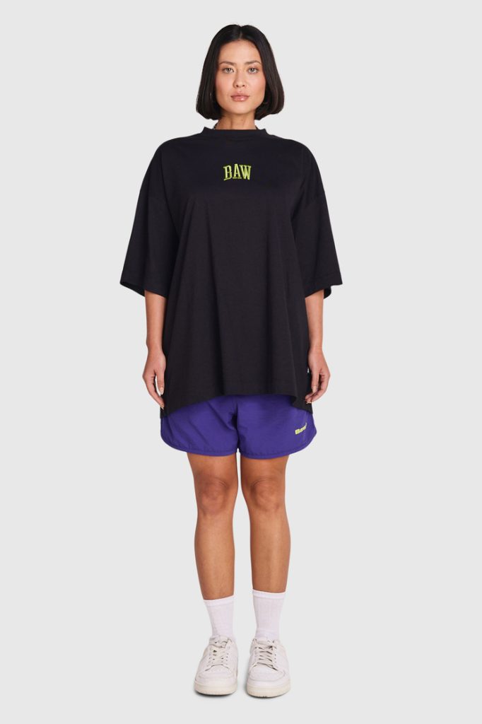 Modelo feminina usando camiseta oversized preta e short roxo