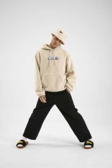 Modelo com hoodie bege e calças largas em estúdio.