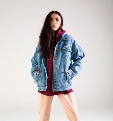 Modelo usando jaqueta jeans e moletom vermelho.