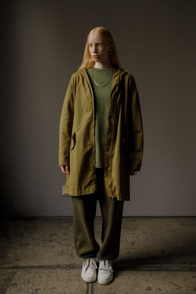 Modelo com roupas verdes em ambiente minimalista