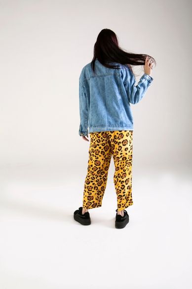 Mulher com jaqueta jeans e calça estampada de onça.