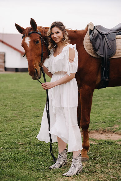 Mulher em vestido branco ao lado de cavalo
