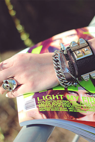 Braço com pulseiras e revista de moda ao fundo