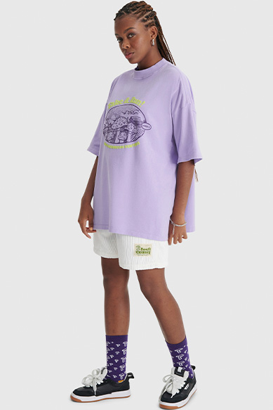 Jovem com camiseta roxa e short branco estilo casual.