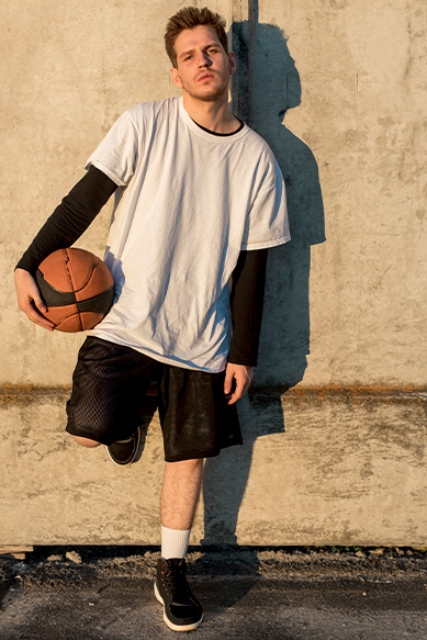 Jovem em roupa de basquete segurando bola.