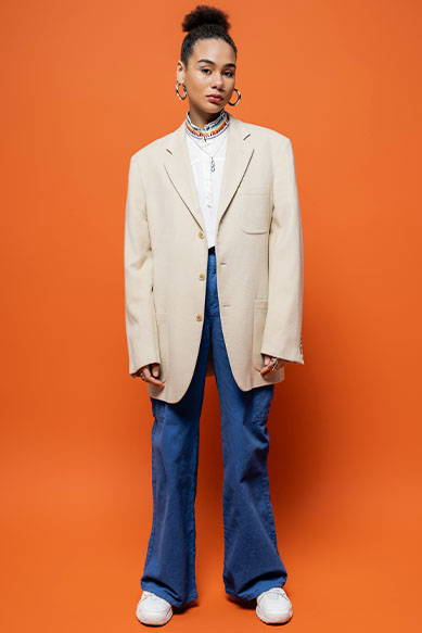 Jovem usando blazer claro sobre fundo laranja