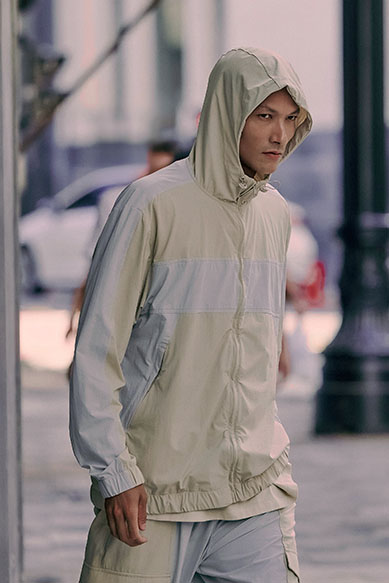 Jovem caminhando com jaqueta leve e capuz