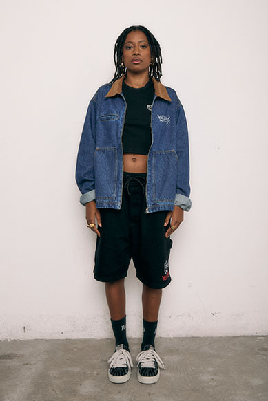 Jovem com jaqueta jeans posando em fundo claro