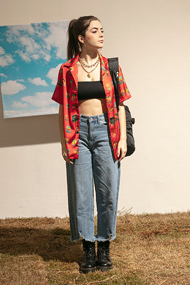 Jovem com camisa vermelha e jeans largos em ambiente externo