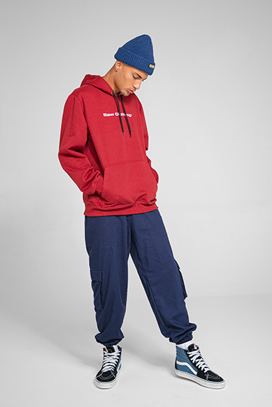 Jovem com moletom vermelho e calça azul na moda urbana.