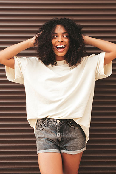 Jovem sorridente com camiseta e shorts em fundo listrado