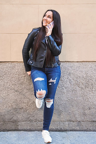 Jovem sorridente usando jaqueta de couro e jeans rasgado.
