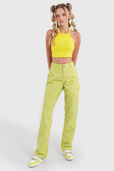 Jovem com top amarelo e calça xadrez verde-limão