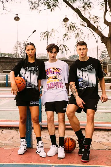 Três jovens em quadra de basquete com roupas urbanas