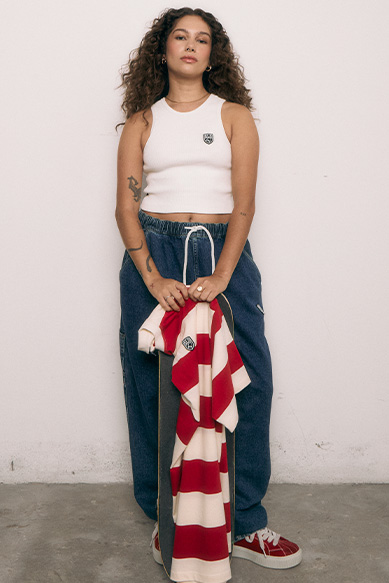 Modelo vestindo blusa e calça casual com camiseta na mão.