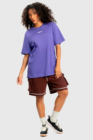 Modelo usando camiseta roxa e shorts marrons