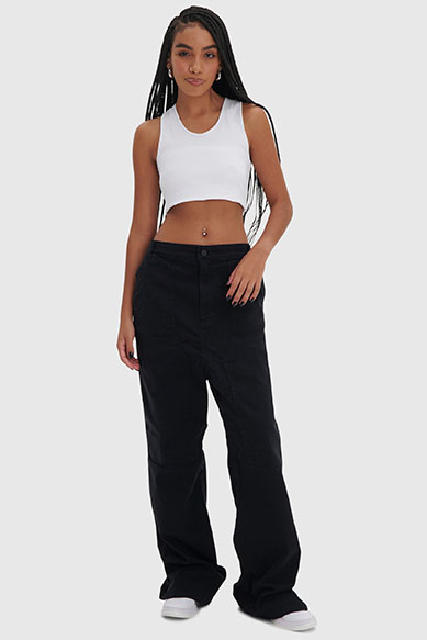 Modelo feminina com blusa branca e calça preta larga.