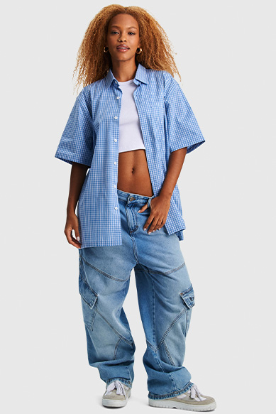 Modelo feminino usando camisa xadrez e calça larga.