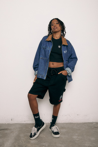 Modelo com jaqueta jeans e shorts em estúdio