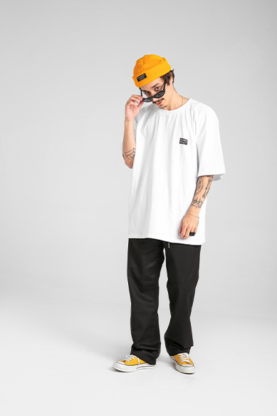 Modelo masculino com camiseta branca e boné amarelo.