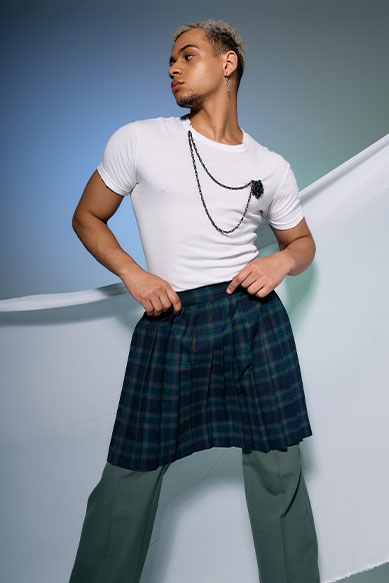 Modelo masculino usando camiseta e saia xadrez