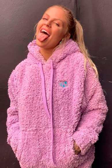 Modelo com moletom rosa, mostrando língua e sorriso.