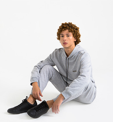 Jovem modelo em moletom cinza sentando no chão