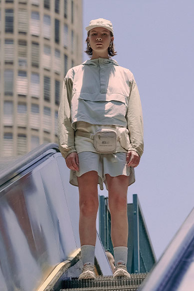 Modelo usando roupas urbanas claras em escada rolante.