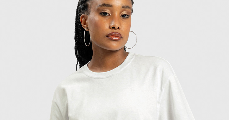 Mulher usando camiseta branca em fundo neutro.