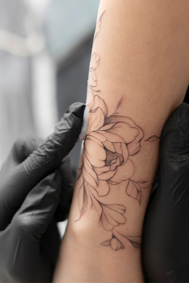 Tatuagem de flor sendo feita em braço humano