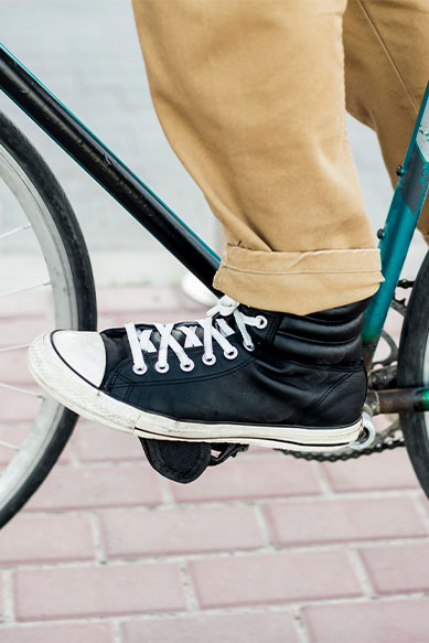 Pé em tênis preto sobre pedal de bicicleta