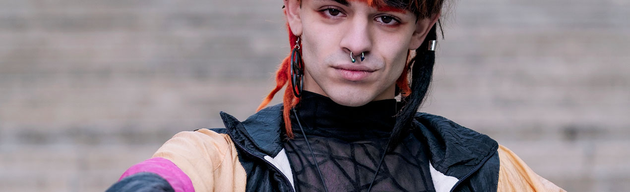 Jovem com cabelo colorido e piercings estilizados.