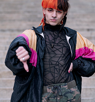Jovem com cabelo colorido e piercings estilizados.