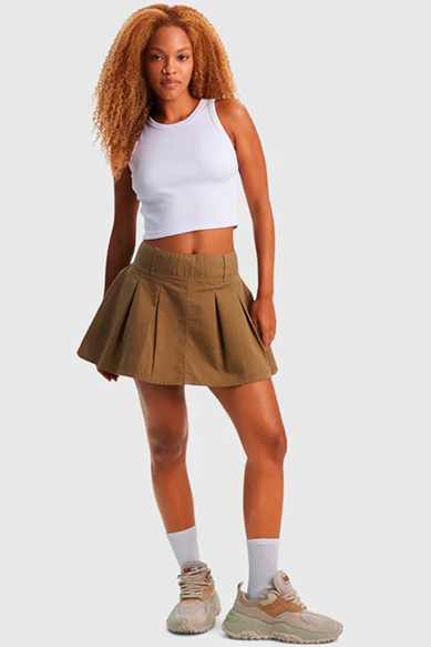 Mulher com blusa branca e saia plissada marrons