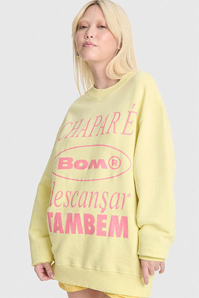 Moça usando moletom amarelo com estampa colorida.