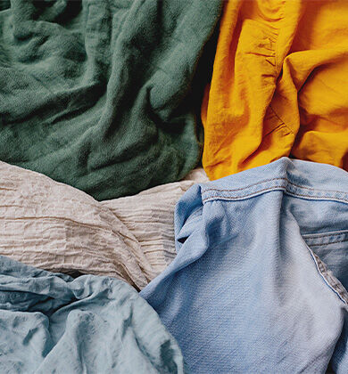 Diversas roupas em tecidos coloridos amontoados