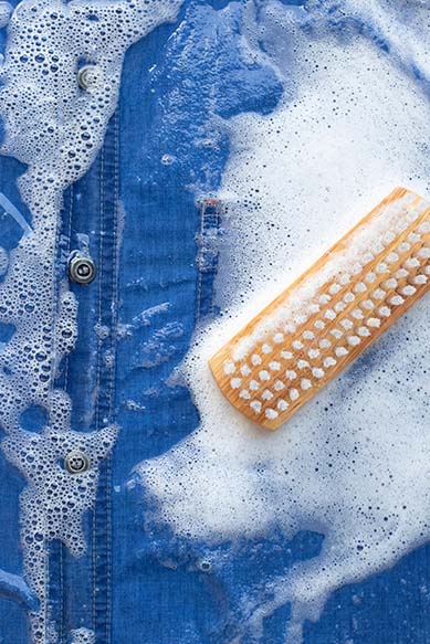 Camisa jeans com sabão e escova para limpeza.