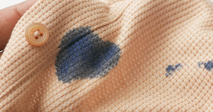 Mancha de tinta em tecido laranja com botão